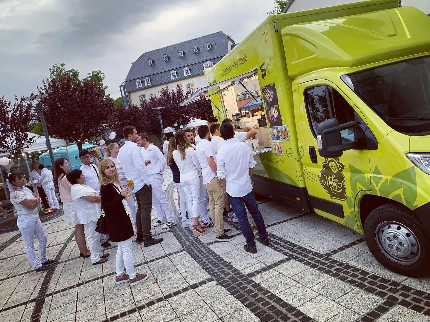 Green foodtruck with a bunch of people waiting
